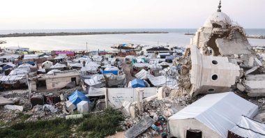 Members of the displaced Palestinian al-Ghafir family sit together to break their Ramadan fast during iftar beside their tent, erected amid the ruins of the al-Hasayna Mosque, Gaza City, Palestine, Feb. 21, 2026. (AFP Photo)
