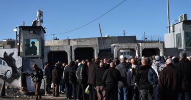 Israeli soldiers stand guard as Palestinians wait in line to cross at the Israeli checkpoint of Qalandia between the West Bank and Jerusalem, to attend the first Friday prayer of Ramadan in Al Aqsa Mosque in Jerusalem, Feb. 20, 2026. (EPA Photo)