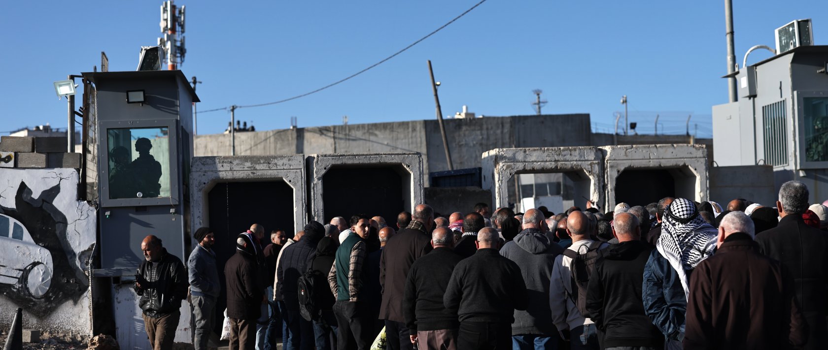 Israeli soldiers stand guard as Palestinians wait in line to cross at the Israeli checkpoint of Qalandia between the West Bank and Jerusalem, to attend the first Friday prayer of Ramadan in Al Aqsa Mosque in Jerusalem, Feb. 20, 2026. (EPA Photo)