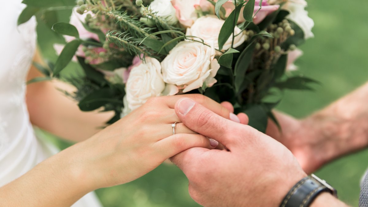 Newlyweds hold hands during a wedding celebration. (Shutterstock Photo)