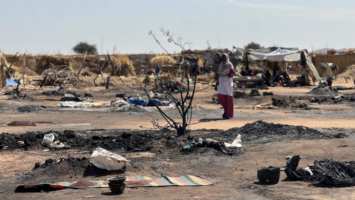 A displaced Sudanese woman who left el-Fasher after its fall with others, walks amid the remains of a fire that broke out at a camp in Tawila, Sudan, Feb. 11, 2026. (AFP Photo)