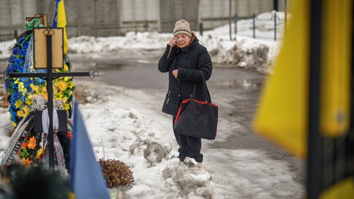 A woman reacts as she stands infront of a grave on the Alley of Heroes at a local cemetery to pay tribute to the victims of the Russian invasion, in the town of Bucha, Kyiv region, Ukraine, Feb. 24, 2026. (Reuters Photo)