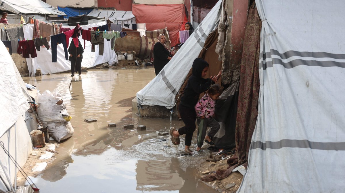 Children make their way through a waterlogged alley at a makeshift camp sheltering displaced Palestinians in Khan Younis, southern Gaza Strip, Feb. 24, 2026. (AFP Photo)