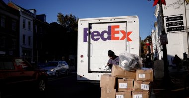 A driver of FedEx stands with packages near a delivery truck during Black Friday preparations in the Georgetown neighborhood of Washington, U.S., Nov. 26, 2024. (Reuters Photo)