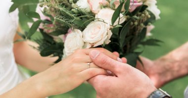 Newlyweds hold hands during a wedding celebration. (Shutterstock Photo)