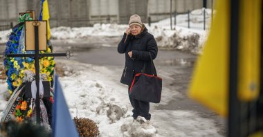 A woman reacts as she stands infront of a grave on the Alley of Heroes at a local cemetery to pay tribute to the victims of the Russian invasion, in the town of Bucha, Kyiv region, Ukraine, Feb. 24, 2026. (Reuters Photo)