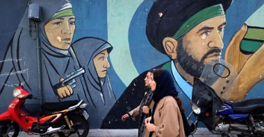 Iranian women walk past a mural depicting Iranian revolutionary female soldiers in Tehran, Iran, Feb. 25, 2026. (AFP Photo)