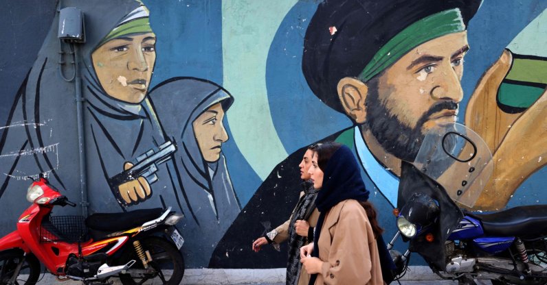 Iranian women walk past a mural depicting Iranian revolutionary female soldiers in Tehran, Iran, Feb. 25, 2026. (AFP Photo)