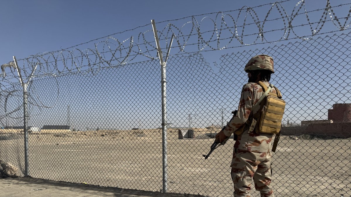 A Pakistani paramilitary soldier stands guard as Afghans arrested for illegally crossing into Iran through the Pak-Iran border line up to be sent back to Afghanistan at the Pak-Afghan border in Chaman, Feb. 24, 2026. (EPA Photo)