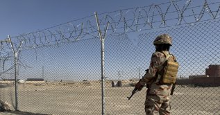 A Pakistani paramilitary soldier stands guard as Afghans arrested for illegally crossing into Iran through the Pak-Iran border line up to be sent back to Afghanistan at the Pak-Afghan border in Chaman, Feb. 24, 2026. (EPA Photo)