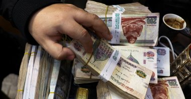 Egyptian pounds and the hand of a gold vendor at a jewelry shop, Cairo, Egypt, Feb. 5, 2026. (Reuters Photo)