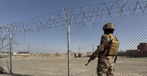 A Pakistani paramilitary soldier stands guard as Afghans arrested for illegally crossing into Iran through the Pak-Iran border line up to be sent back to Afghanistan at the Pak-Afghan border in Chaman, Feb. 24, 2026. (EPA Photo)