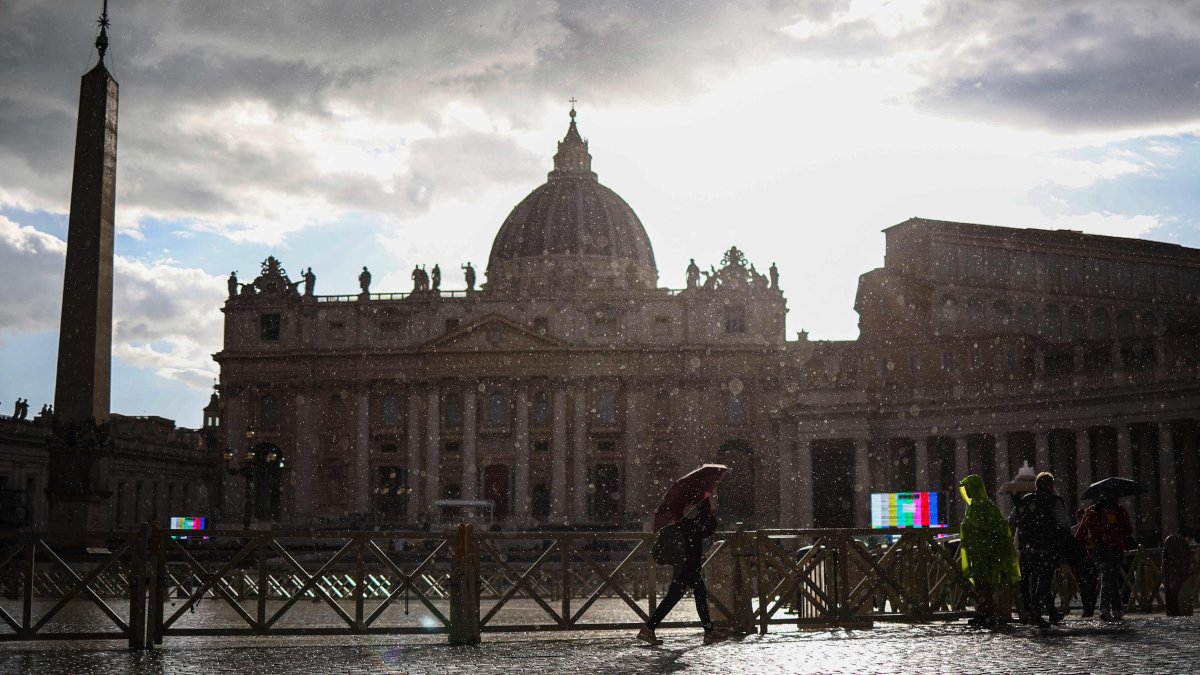 A woman holds an umbrella to shelter from the rain as she walks with St. Peter's Basilica in the background near the Vatican, Rome, Italy, April 24, 2025. (AFP Photo)