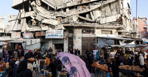 Palestinians shop for food beneath a destroyed building in Gaza City's Zawiya market on Feb. 18, 2026. (AFP Photo)