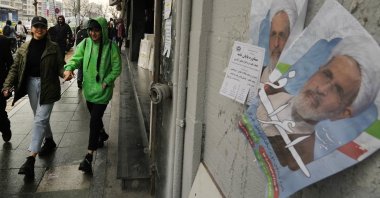 Women walk past electoral posters of Ayatollah Alireza Arafi, in downtown Tehran, Iran, Feb. 21, 2024. (AP Photo)