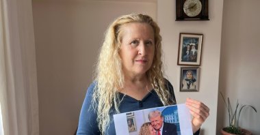 Necla Özmen holds an AI-generated image showing herself standing beside Donald Trump as she speaks publicly about her paternity claim, Ankara, Türkiye, March 1, 2026. (IHA Photo) 