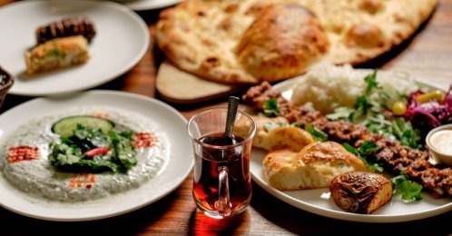 A glass of Turkish tea served alongside a spread of traditional dishes, including kebab, balloon lavash, haydari and baklava. (Shutterstock Photo)
