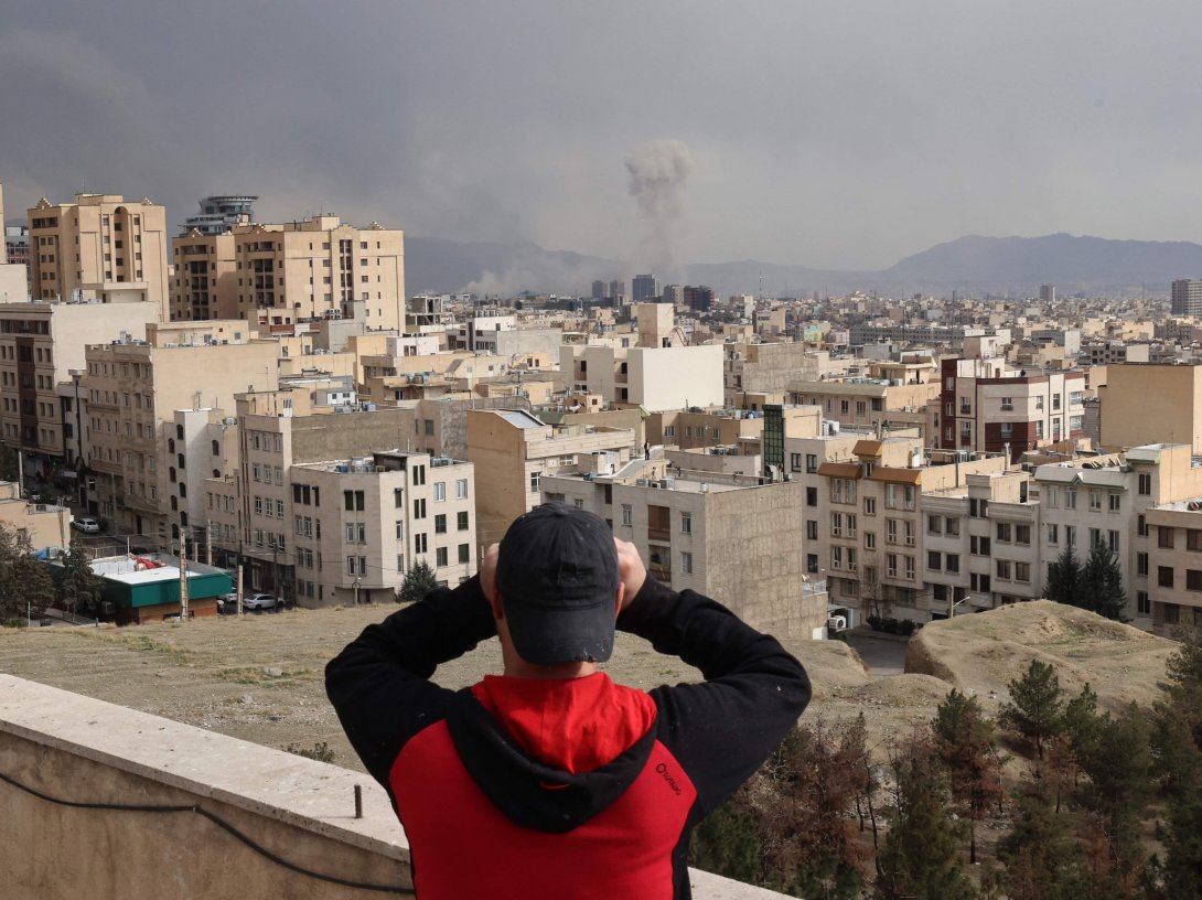 A man looks through binoculars as a plume of smoke rises after a military strike on the capital Tehran, Iran, March 2, 2026. (AFP Photo)