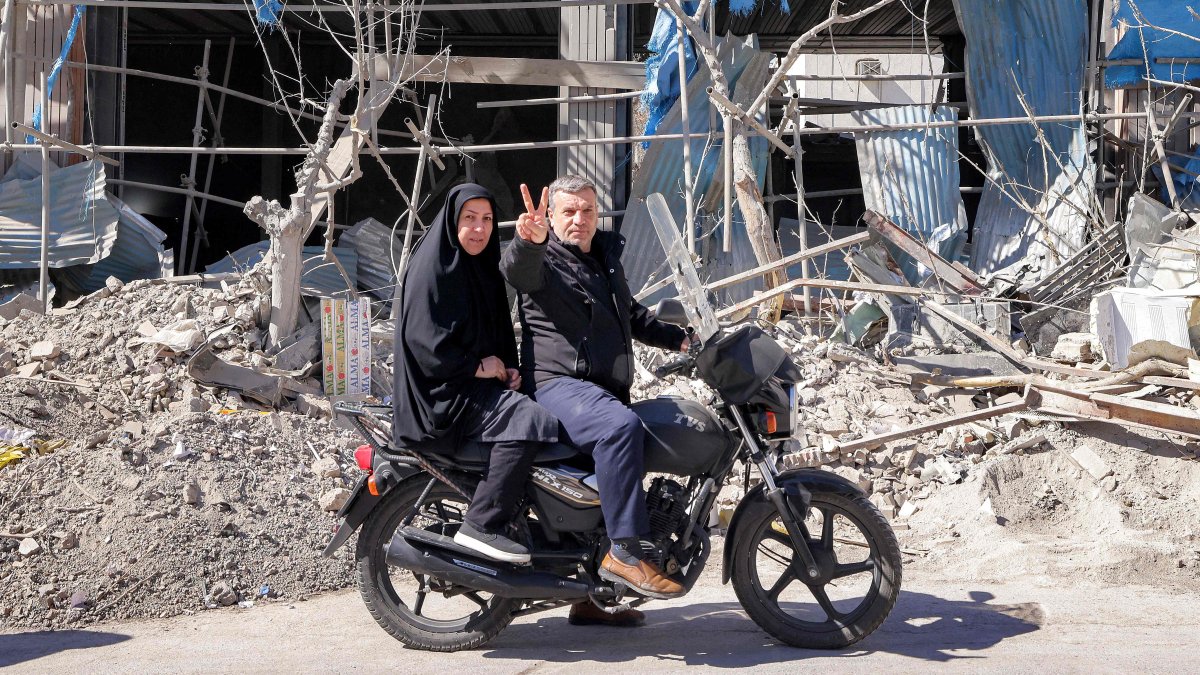 A man reacts while riding a motorcycle past buildings collapsed and damaged in U.S.-Israeli strikes near Ferdowsi Square in Tehran, Iran, March 3, 2026. (AFP Photo)