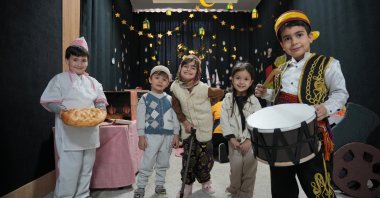 Children dressed in Ramadan-themed costumes, including a pide baker (L) and a traditional drummer, known as a “Ramazan davulcusu” (R), pose in front of Ramadan decorations at a school in Isparta, western Türkiye, Feb. 18, 2026. (AA Photo)