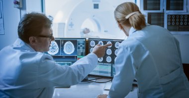 In this stock photo, doctors review brain scan results in the control room while the patient undergoes MRI/CT. (Shutterstock Photo)