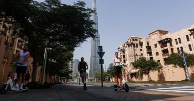 People ride scooters on a street with the Burj Khalifa in the background, after an Iranian attack, following the U.S.-Israeli strikes on Iran, Dubai, United Arab Emirates, March 1, 2026. (Reuters Photo)