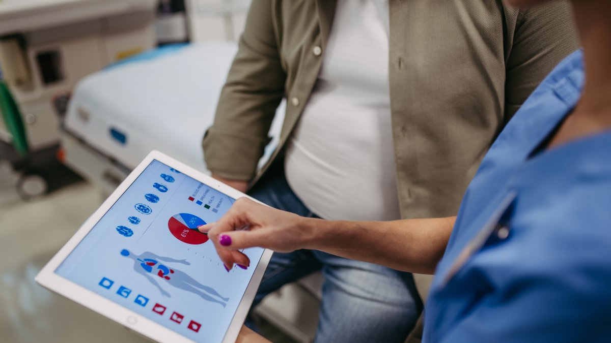 A doctor consults with an overweight patient, reviewing test results. (Shutterstock Photo)