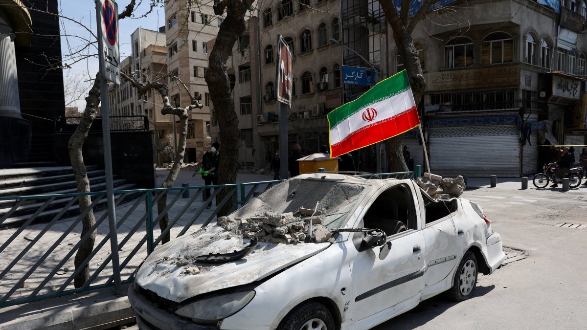 An Iranian flag is mounted on a damaged car following a strike on a police station, amid the U.S.-Israeli conflict with Iran, in Tehran, Iran, March 4, 2026. (Reuters Photo)