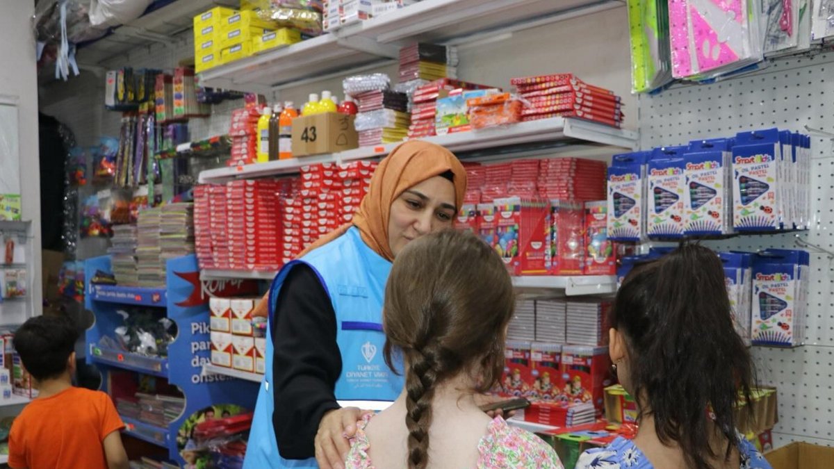 A Türkiye Diyanet Foundation team member helps orphaned children buy stationery during a school support activity, Türkiye, March 5, 2026. (AA Photo)