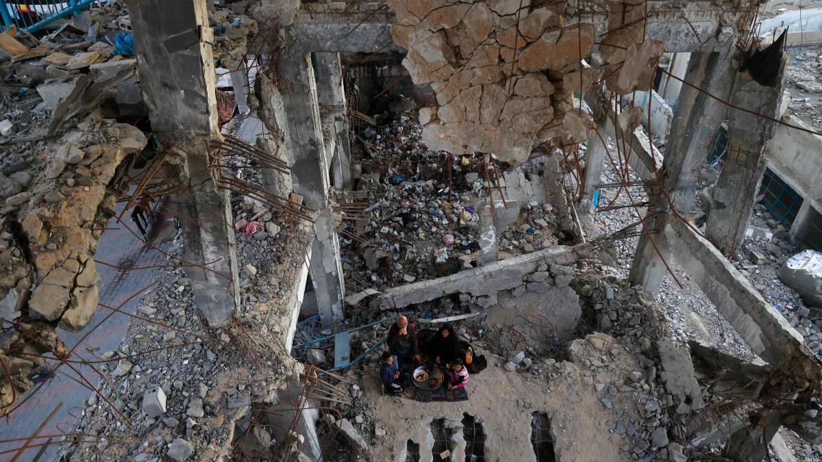 A displaced Palestinian family gather to sit for the "iftar" fast-breaking meal during the Muslim holy month of Ramadan, amidst the destruction in Bureij refugee camp in the central Gaza Strip, Feb. 25, 2026. (AFP File Photo)