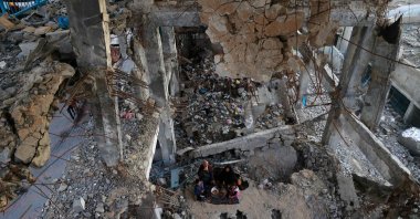 A displaced Palestinian family gather to sit for the "iftar" fast-breaking meal during the Muslim holy month of Ramadan, amidst the destruction in Bureij refugee camp in the central Gaza Strip, Feb. 25, 2026. (AFP File Photo)