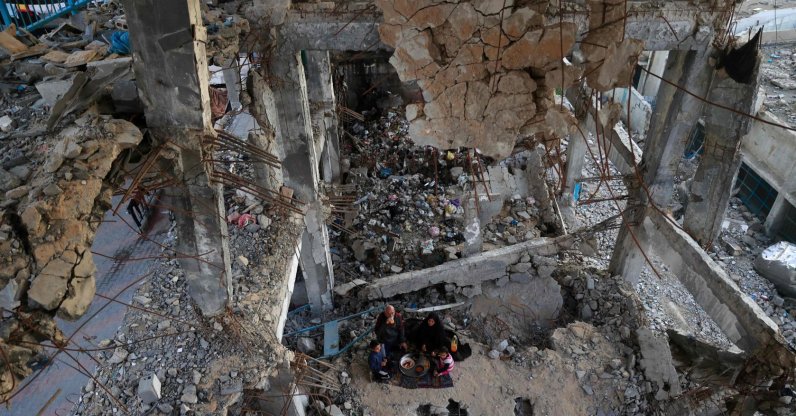 A displaced Palestinian family gather to sit for the "iftar" fast-breaking meal during the Muslim holy month of Ramadan, amidst the destruction in Bureij refugee camp in the central Gaza Strip, Feb. 25, 2026. (AFP File Photo)