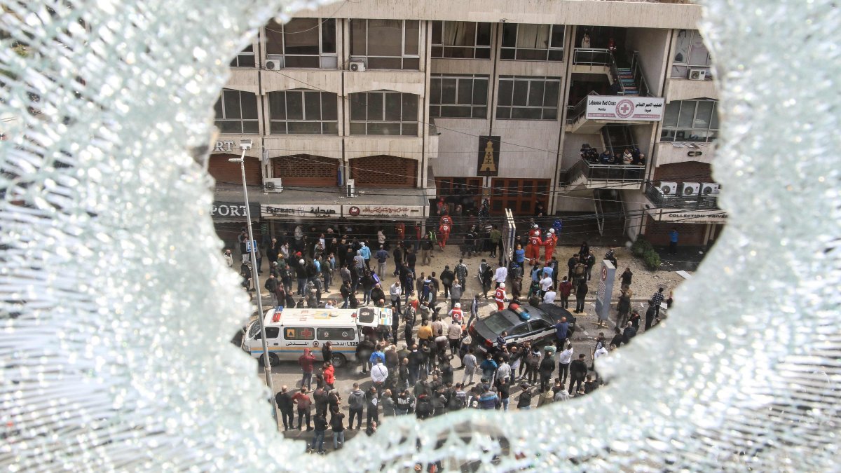A shattered window overlooks first aid responders and security forces responding near a building that was targeted by an Israeli airstrike, Sidon, Lebanon, March 6, 2026. (AFP Photo)