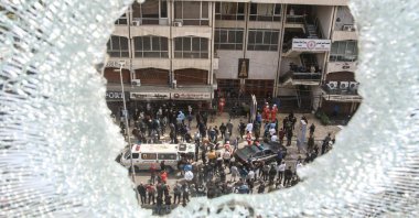 A shattered window overlooks first aid responders and security forces responding near a building that was targeted by an Israeli airstrike, Sidon, Lebanon, March 6, 2026. (AFP Photo)