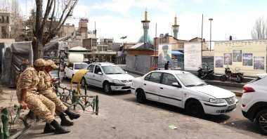 Two Iranian soldiers look at their mobile phone as they sit close to an image of Iran&amp;#039;s slain supreme leader Ayatollah Ali Khamenei (R), along a street close to Tajrish Square in Tehran, Iran, March 7, 2026. (AFP Photo)
