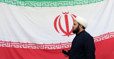 An Iranian cleric walks next to the national flag during a protest in front of the destroyed Gandhi Hospital by a U.S.-Israel airstrike in Tehran, Iran, March 7, 2026. (EPA Photo)