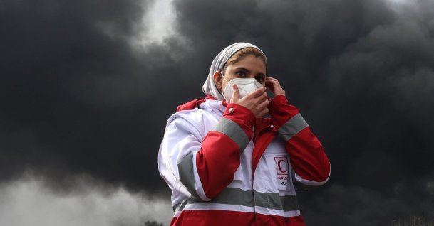 A member of Iran's Red Crescent walks as smoke still rises from Shahran Oil Refinery, in Tehran, Iran, March 8, 2026. (EPA Photo)