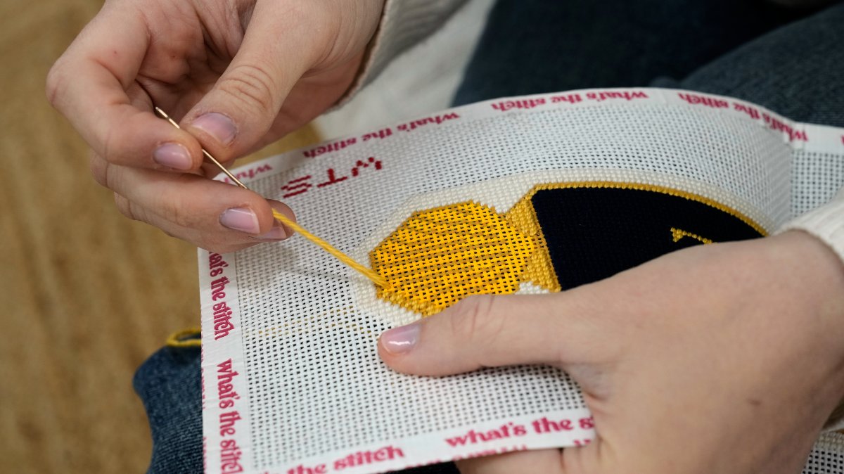 Emma MacTaggart, founder of What's the Stitch needlepoint business, works on a needlepoint in her studio, New York, U.S., Feb. 9, 2026. (AP Photo)