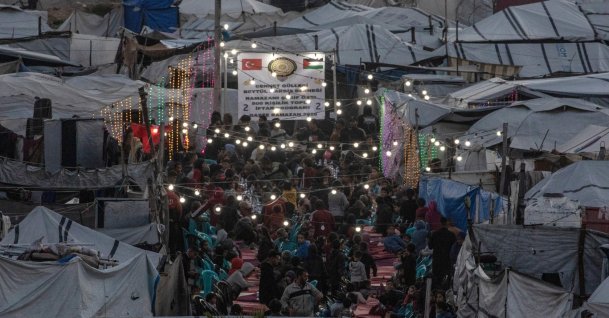 Displaced Palestinian people gather between makeshift tents to break their fast with an iftar meal together during the holy fasting month of Ramadan, the west of Gaza, Palestine, March 6, 2026. (EPA Photo)