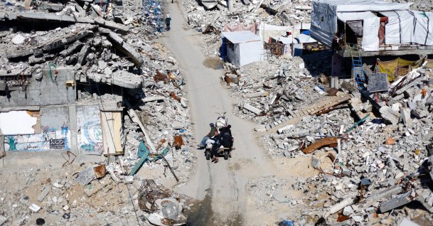 Palestinians ride past the rubble of residential buildings destroyed during the two-year Israeli offensive, in Jabalia, northern Gaza Strip, March 8, 2026. (Reuters Photo)