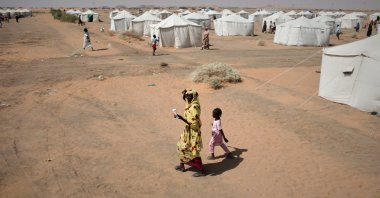 A war-displaced woman and a child walk in the newly established el-Afadh camp in al Dabbah, in Sudan's Northern State, Sudan, Nov. 13, 2025. (AP Photo)