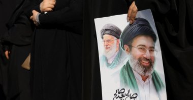 A woman holds an image of Iran's new supreme leader, Mojtaba Khamenei, alongside late Iranian Supreme Leader Ayatollah Ali Khamenei, during a funeral ceremony for the Iranian military commanders who were killed in strikes, amid the U.S.-Israeli conflict with Iran, in Tehran, Iran, March 11, 2026. (Reuters Photo)