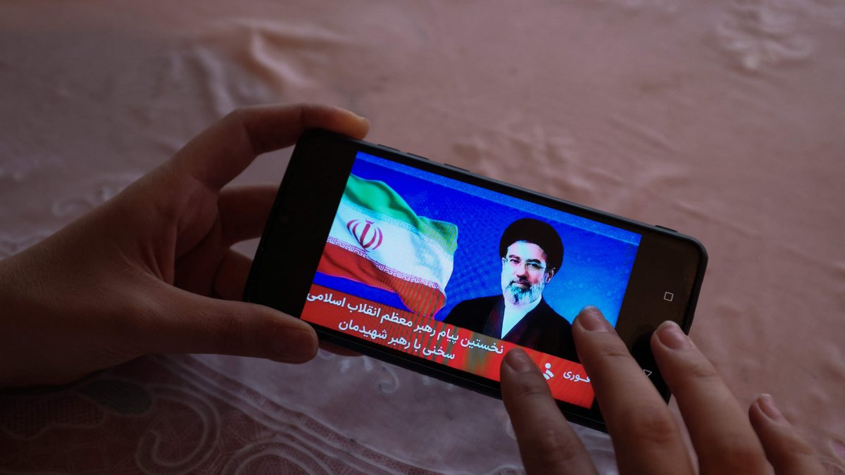 A girl watches a televised statement by Iran's new supreme leader, Mojtaba Khamenei, on a mobile phone, Tehran, Iran, March 12, 2026. (AFP Photo)