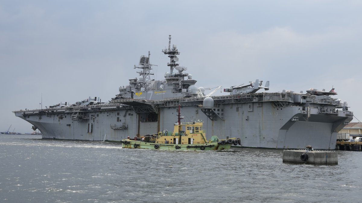 A tugboat passes by a U.S. Navy USS Tripoli (LHA-7) amphibious assault ship during a port call in Manila, Philippines, Tuesday, Sept. 27, 2022. (AP File Photo)