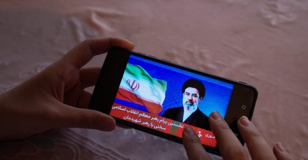 A girl watches a televised statement by Iran's new supreme leader, Mojtaba Khamenei, on a mobile phone, Tehran, Iran, March 12, 2026. (AFP Photo)