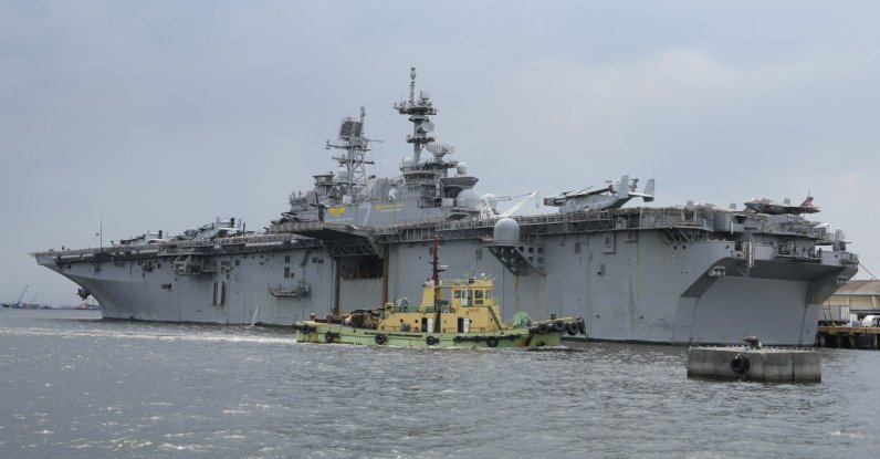 A tugboat passes by a U.S. Navy USS Tripoli (LHA-7) amphibious assault ship during a port call in Manila, Philippines, Tuesday, Sept. 27, 2022. (AP File Photo)