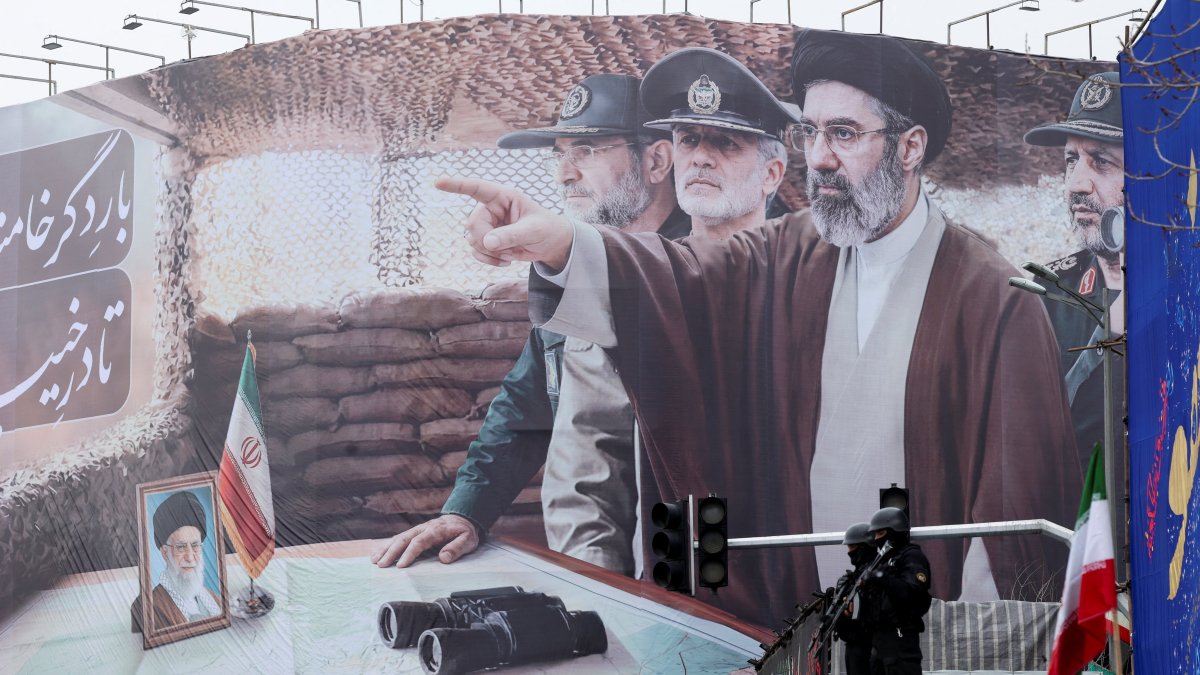 Security personnel stand guard in front of a banner with an image of Iran's new Supreme Leader Mojtaba Khamenei and his father, Iran's late Supreme Leader Ayatollah Ali Khamenei, Tehran, Iran, March 13, 2026. (Reuters Photo)