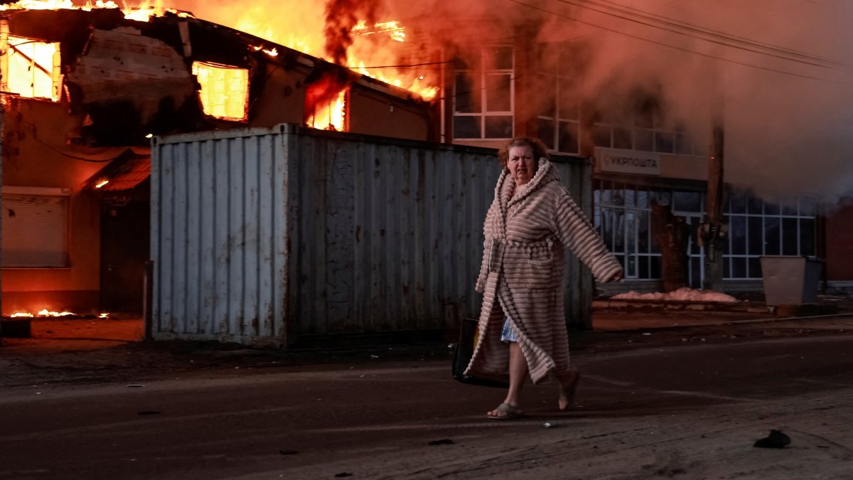 A woman walks past a burning house at the site of Russian missile and drone strike, amid Russia's attack on Ukraine, in the town of Brovary, in Kyiv region, Ukraine March 14, 2026. REUTERS/Yan Dobronosov