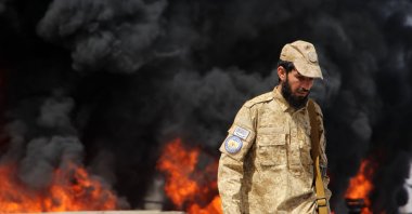 A Taliban security official stands guard as flames rise from a fuel depot allegedly hit in a Pakistani airstrike near Kandahar airport, Kandahar, Afghanistan, March 13, 2026. (EPA Photo)