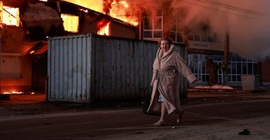 A woman walks past a burning house at the site of Russian missile and drone strike, amid Russia's attack on Ukraine, in the town of Brovary, in Kyiv region, Ukraine March 14, 2026. REUTERS/Yan Dobronosov